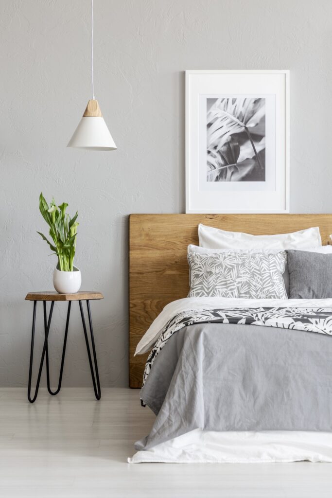 plant on table next to wooden bed in grey bedroom QB7WPCA